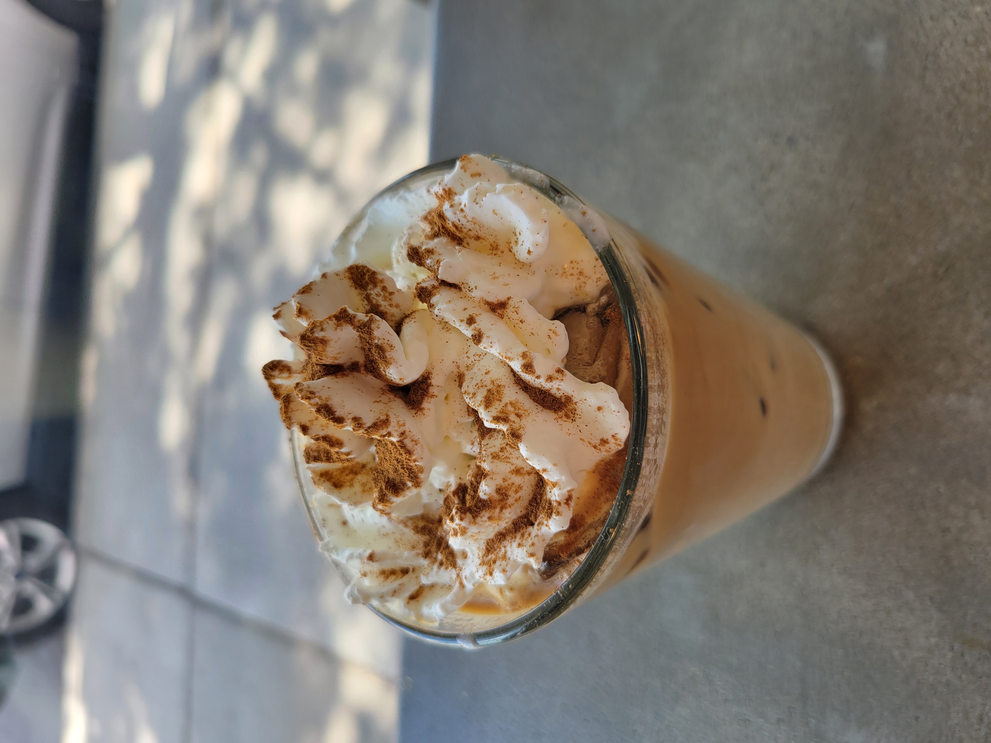 Latte with whipped cream topped with cinnamon in a glass.